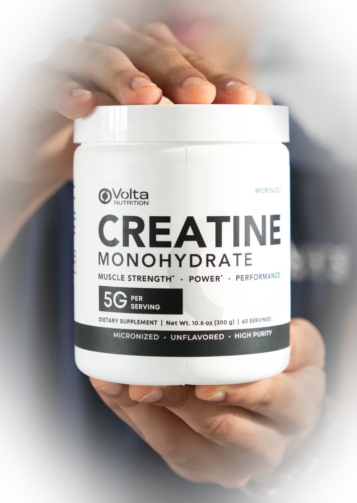 Bote de Volta Creatine sostenido con las dos manos, con la etiqueta de frente